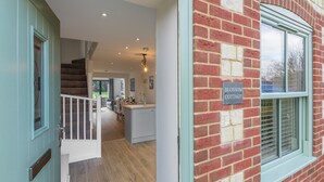 A modern interior with a staircase leading to a kitchen area, a dining space, and a visible sign reading "Blossom Cottage."