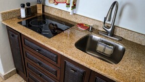 Una cocina con encimeras de granito, un lavamanos de acero inoxidable y un horno empotrado.