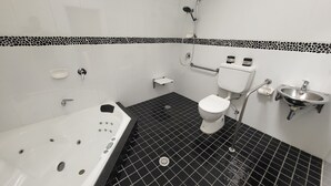Ein Badezimmer mit schwarz-weißen Fliesen, einer weißen Badewanne, einer Toilette, einem Waschbecken und einer Dusche.