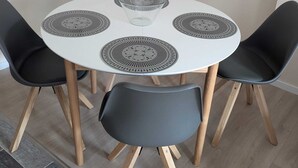 Une table de salle à manger ronde, accompagnée de quatre chaises, chacune dotée d’un siège noir et d’un set de table à motifs.