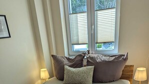 Une chambre à coucher avec un grand lit, deux lampes de chevet et une fenêtre équipée de stores.
