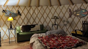 A yurt interior with a bed, green sofa, and decorative items. - Whimsical Wilderness: Wonderful Yurt Stay (Guerneville)