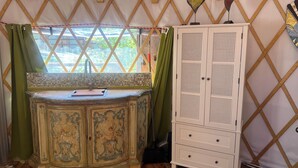 A room with a wooden cabinet with intricate designs, a small sink with a decorative faucet, and a lattice window structure. - Whimsical Wilderness: Wonderful Yurt Stay (Guerneville)