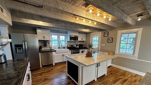 Une cuisine spacieuse avec un plancher en bois, des meubles blancs et un îlot central.