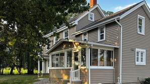 Une maison à deux étages dotée d’un porche abrité, d’une cheminée en pierre et d’une pelouse bien entretenue.