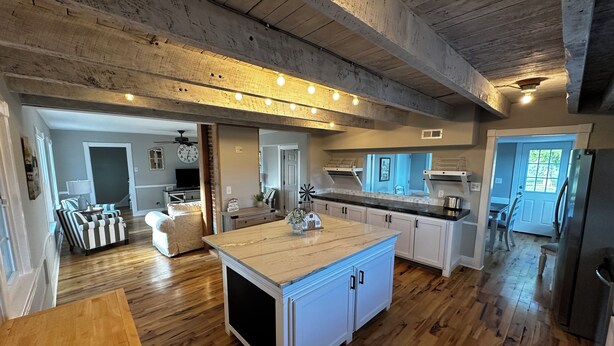 Une cuisine spacieuse avec un plancher en bois, un îlot central et un coin repas avec des chaises.