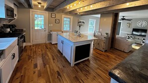 Une cuisine spacieuse avec un plancher en bois, un grand îlot central et un coin repas agrémenté d’un canapé.