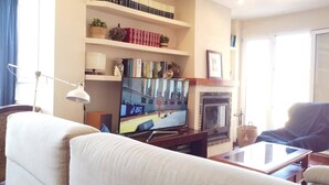 A living room with a flat-screen TV, bookshelves, a fireplace, and a sofa. - Penthouse with exceptional views (La Manga)