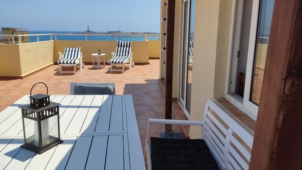 A terrace with white furniture, a table, and a lantern. - Penthouse with exceptional views (La Manga)