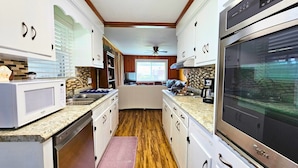 A compact kitchen with white cabinets, a microwave, a stove, and a refrigerator.