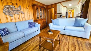 A living room with two light blue sofas, a wooden cabinet, and a wooden floor.