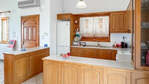 Eine Küche mit Holzausstattung, einem Kühlschrank, einem Spülbecken und einer Arbeitsplatte mit einer Obstschale.