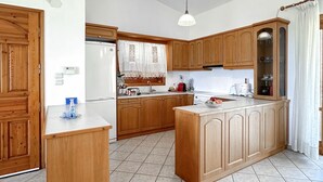 Eine Küche mit Holzausstattung, einer zentralen Kochinsel, einem Kühlschrank und einem Spülbecken.