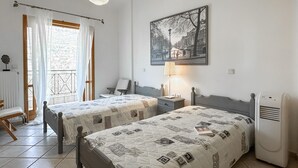 Ein Schlafzimmer mit zwei Betten, einem Fenster mit Vorhängen, einer Wandlampe und einer Heizung.