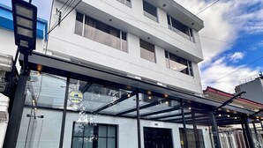 A modern building with a glass facade, outdoor seating area, and a security camera. - Hotel Embajada 44 (Bogotá)