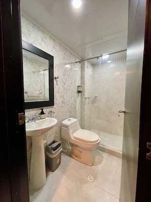 A bathroom with a white sink, toilet, and glass shower enclosure. - Hotel Embajada 44 (Bogotá)