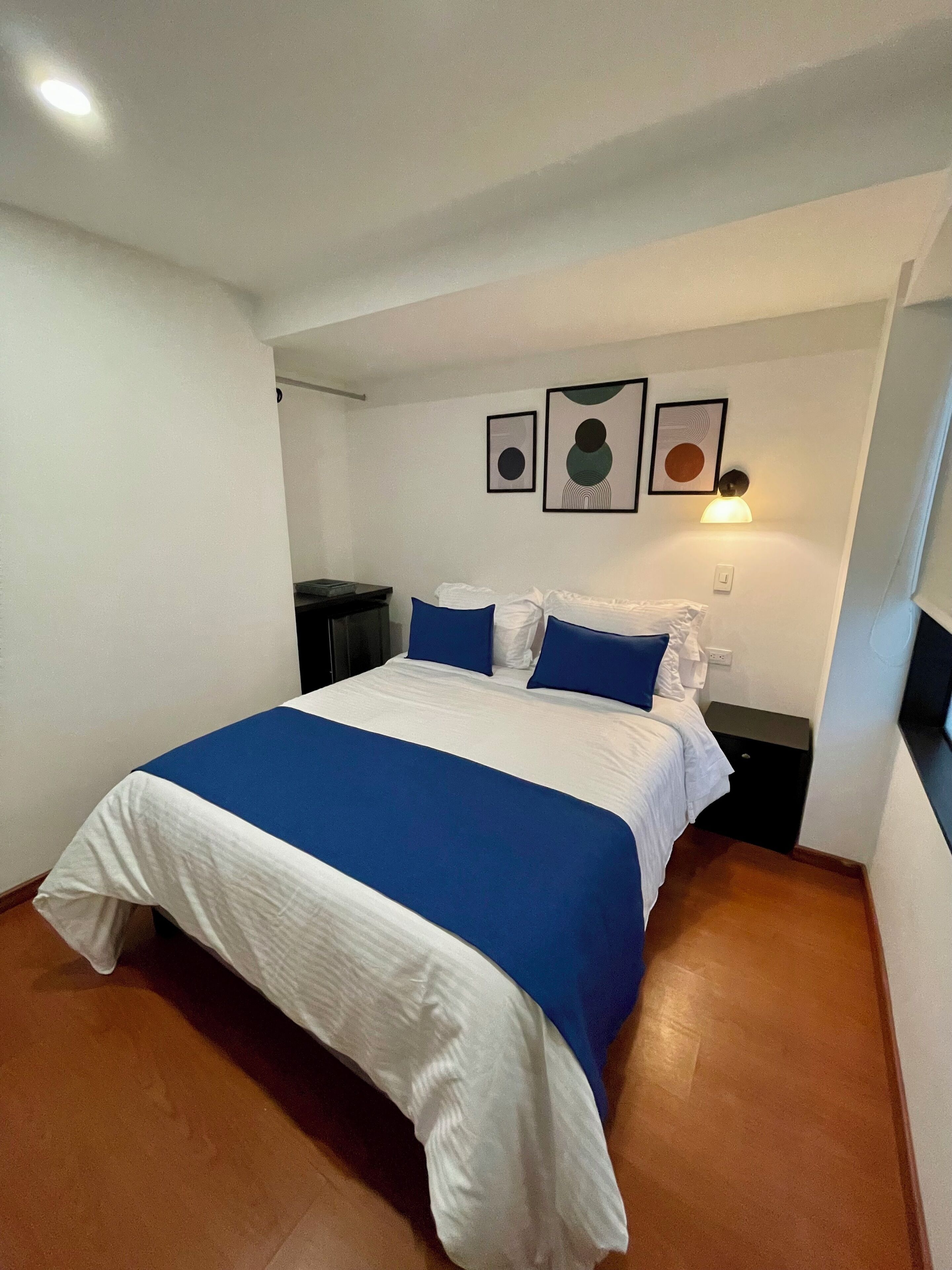 A bedroom with a large bed, white walls, and a ceiling light.