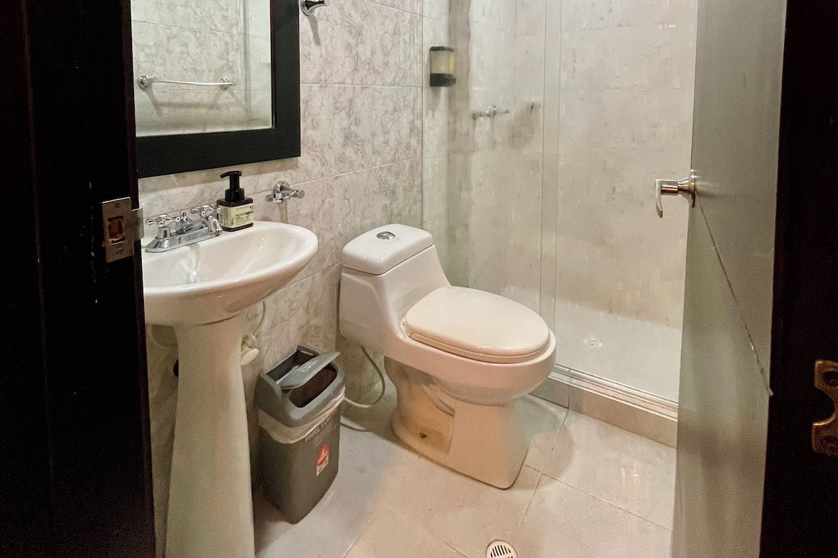 A bathroom with a white sink, toilet, and glass shower enclosure.