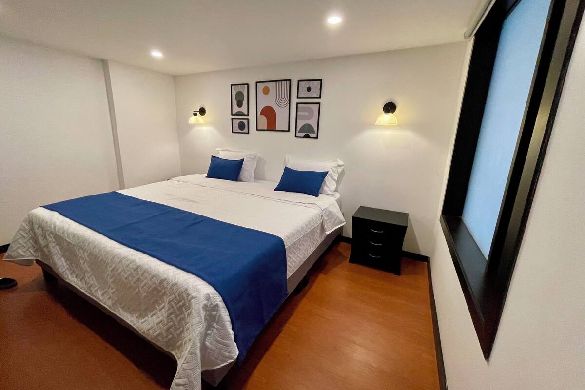 Ein ordentlich eingerichtetes Schlafzimmer mit einem großen Bett, zwei Nachttischen und Wandleuchten.