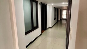A long, well-lit hallway with white walls and large windows. - Hotel Embajada 44 (Bogotá)