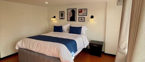 Una habitación de hotel moderna con una cama grande, suelo de madera y una lámpara de techo.