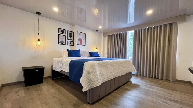 A modern bedroom with a large bed, a bedside table, and a wardrobe. - Hotel Embajada 44 (Bogotá)