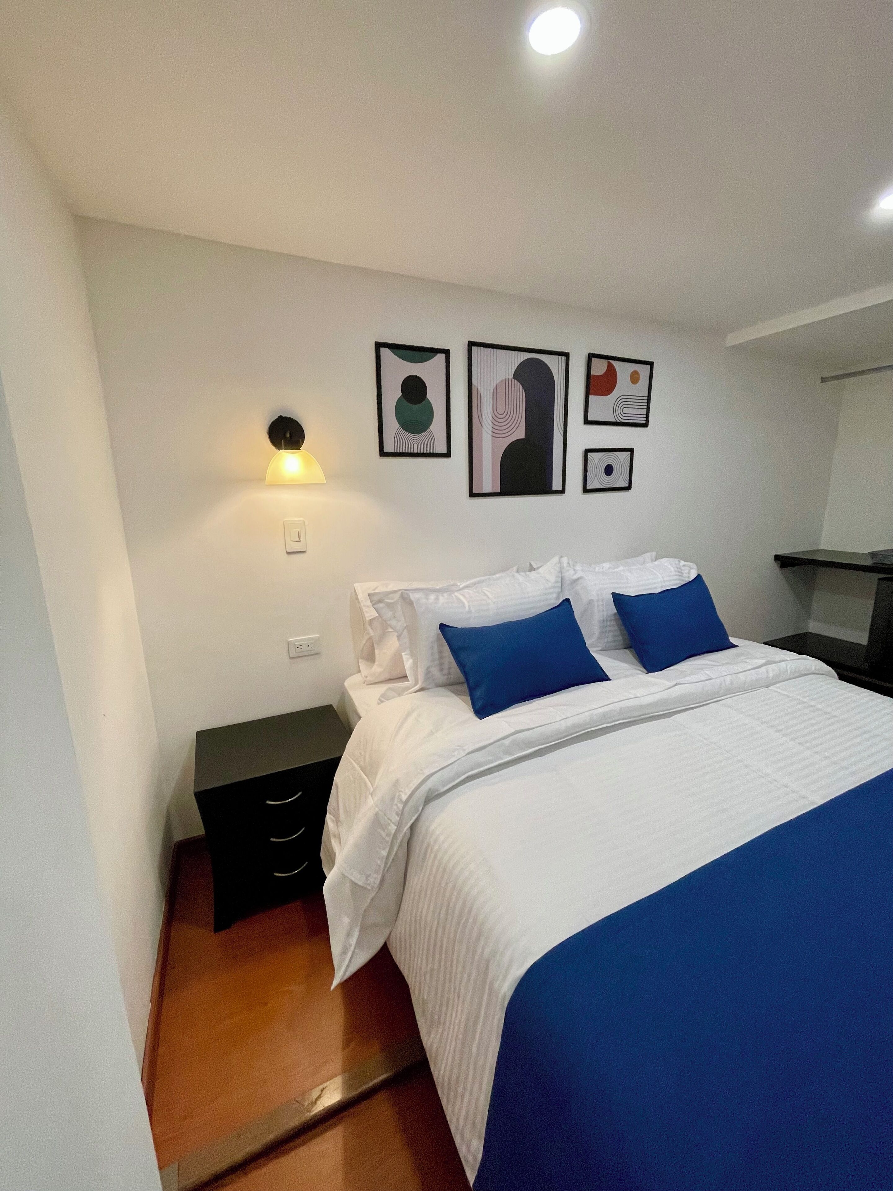 Un dormitorio con cama, mesita de noche y decoración en la pared.