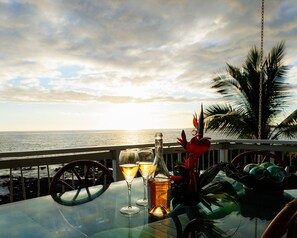 A table with a bottle and glasses, a steering wheel, and a view of the ocean. - Private Oceanfront Home, Sleeps 10, fire pit, minutes to Kailua, backyard beach (Kailua-Kona)