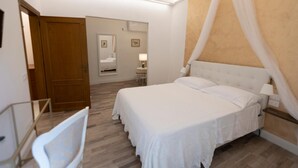 A bedroom with a large bed, a bedside table, a chair, a wooden door, and a mirror. - One Bedroom Apartment (Firenze)