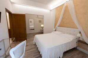 A bedroom with a large bed, a bedside table, a chair, a wooden door, and a mirror. - One Bedroom Apartment (Firenze)