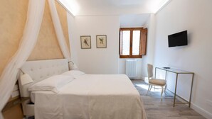 A bedroom with a bed, a chair, a desk, a TV, and two framed pictures on the wall. - One Bedroom Apartment (Firenze)
