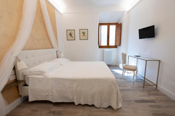 A bedroom with a bed, a chair, a desk, a TV, and two framed pictures on the wall. - One Bedroom Apartment (Firenze)