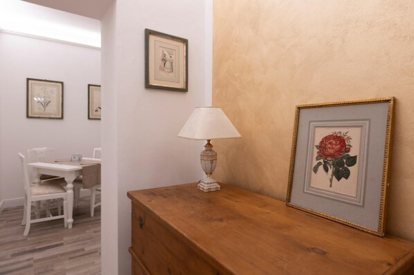 A room with a wooden dresser, a table with chairs, and framed pictures on the wall.
