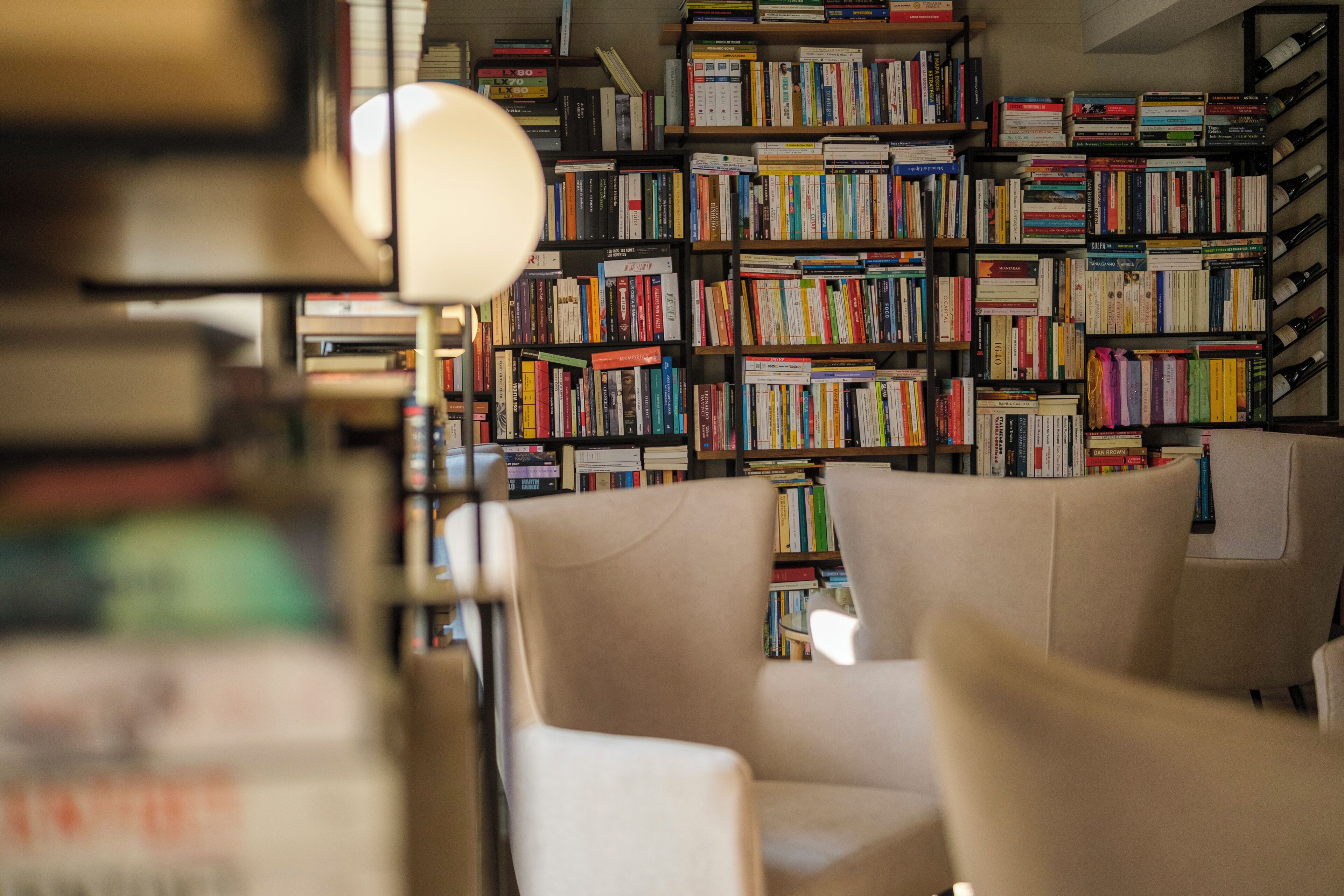 Una biblioteca con estanterías llenas de libros, un escritorio y dos sillas.
