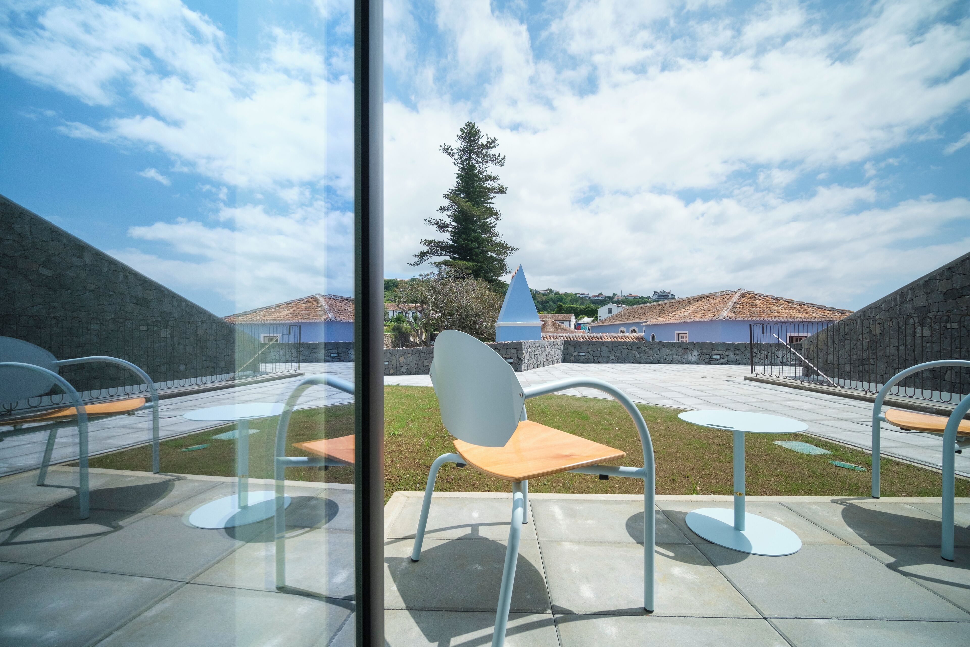Eine Terrasse mit Sitzgelegenheiten im Freien und Blick auf ein Gebäude mit blauem Dach.