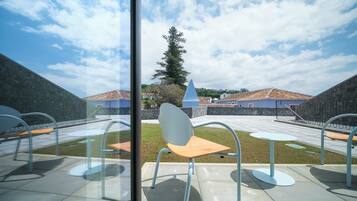 Eine Terrasse mit Sitzgelegenheiten im Freien und Blick auf ein Gebäude mit blauem Dach.