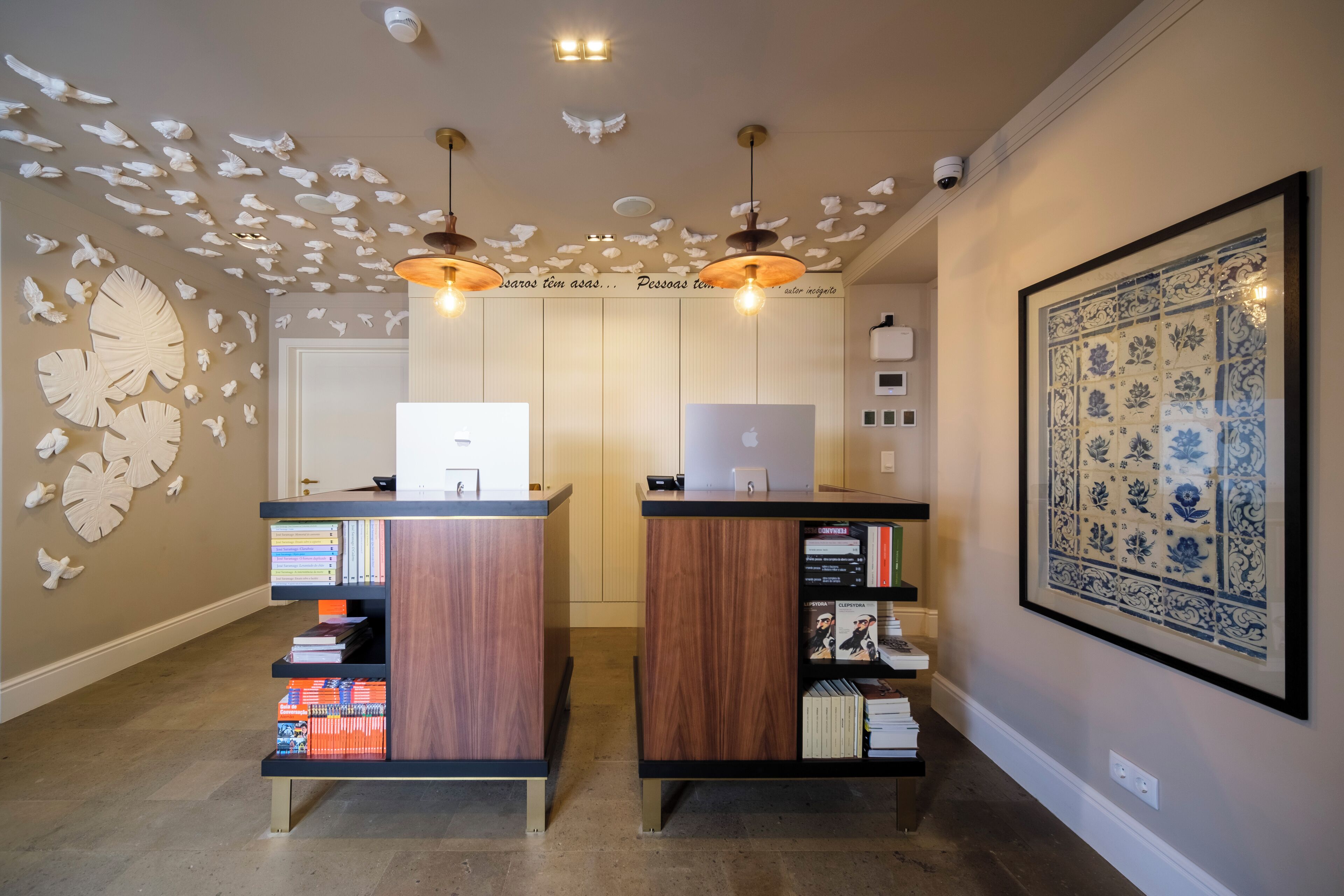 Un área de recepción con dos mostradores de madera, estanterías, decoración mural y luminarias en el techo.