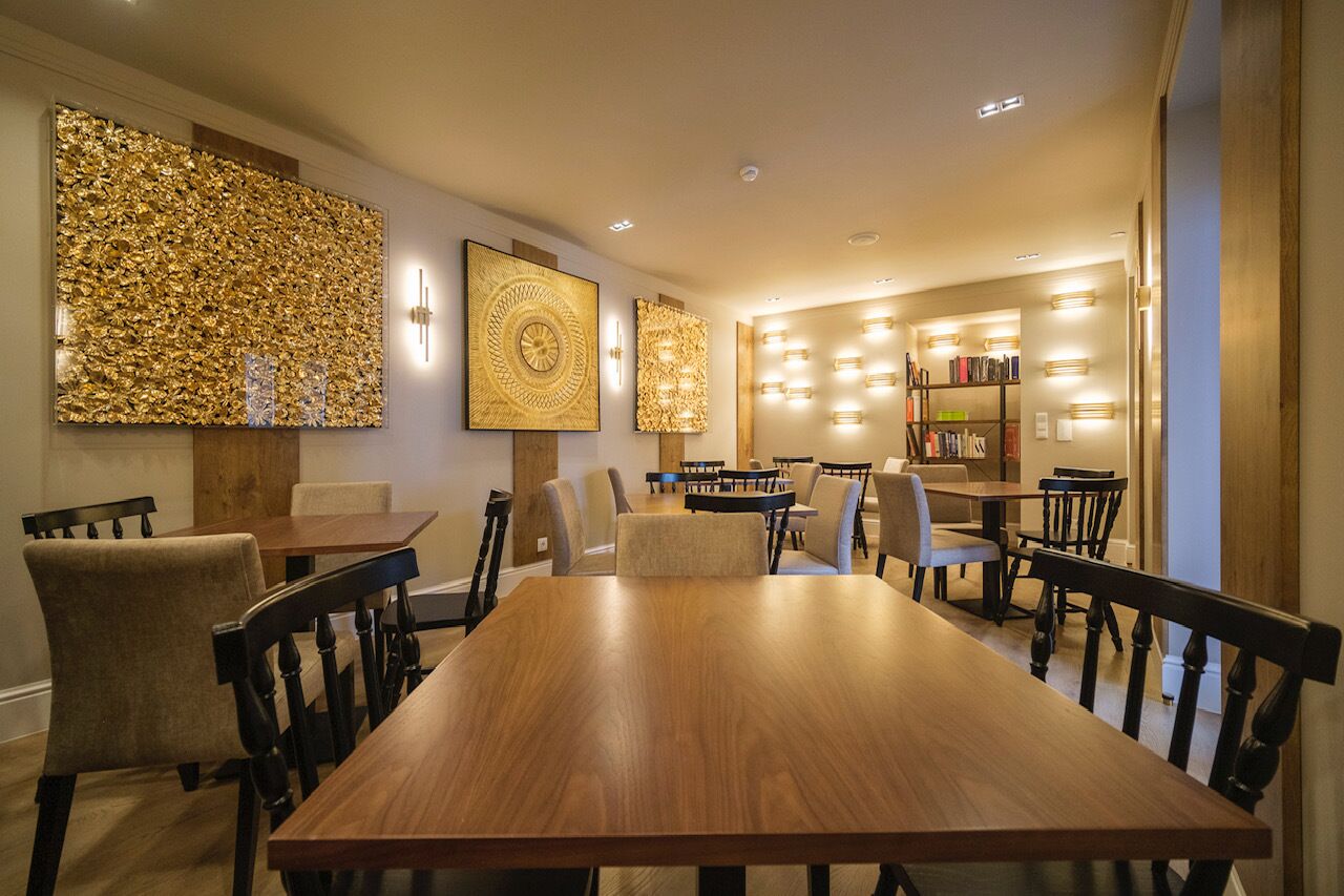 A dining area with a long wooden table, multiple chairs, and a bookshelf filled with books.