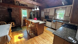 Une cuisine avec un plancher en bois, un îlot central et un coin repas avec des chaises.