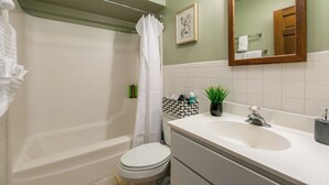 Une salle de bain équipée d’une baignoire, de toilettes, d’un lavabo et d’un rideau de douche.