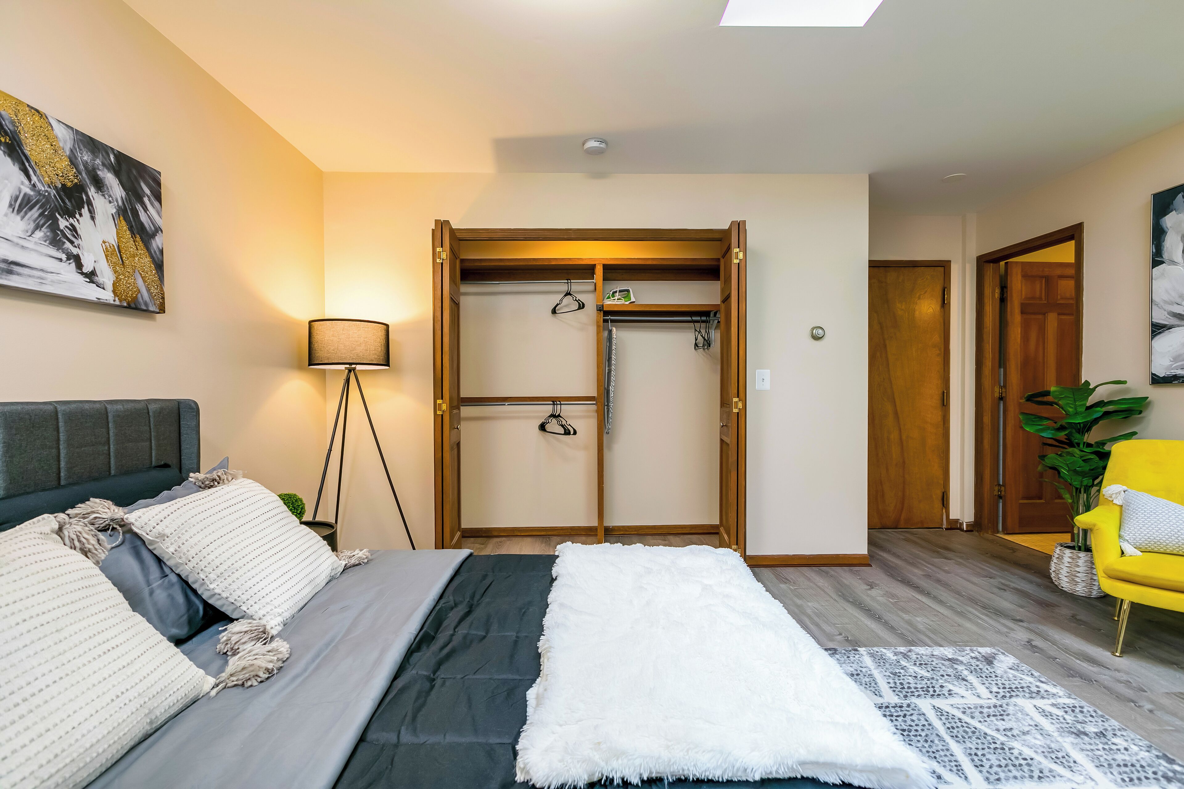 A bedroom with a bed, a wardrobe, a lamp, and a chair.