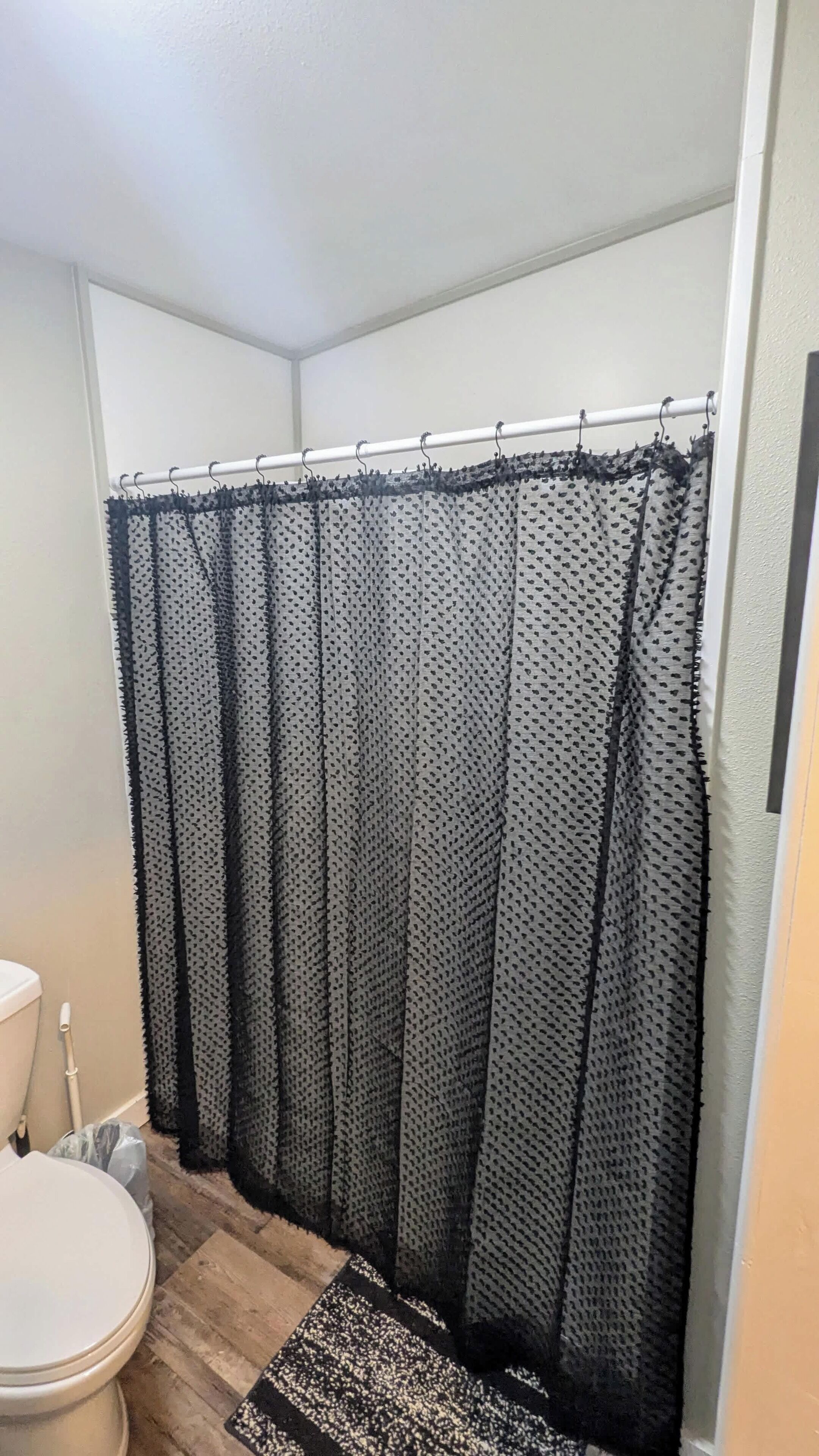 A bathroom with a shower curtain, toilet, and a rug.