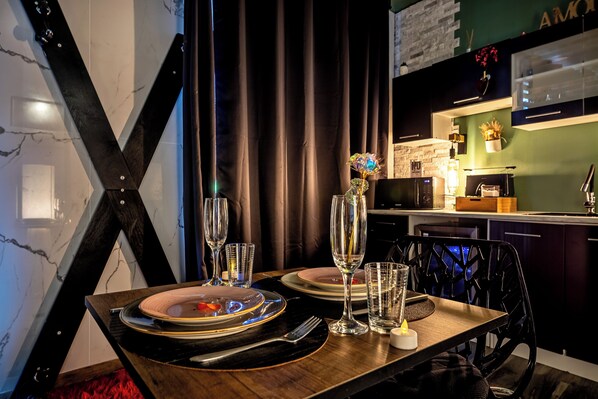 Une table à manger dressée avec des assiettes, des verres et des couverts, un vase rempli de fleurs et une bougie.