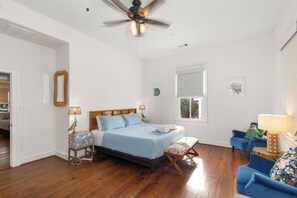 A bedroom with a bed, a ceiling fan, a window, and a blue chair. - Historic Davidson-Penland House - Old Galveston Charm with Modern Amenities (Galveston)