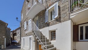 A narrow street with stone buildings, a staircase leading to a second-floor balcony, and a small outdoor seating area. - 2 bedroom beautiful home in Sollacaro (Sollacaro)