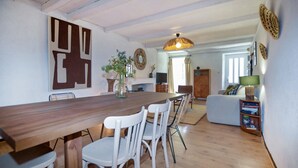 A dining area with a wooden table and white chairs, a living room with a sofa and a television, and a kitchen area with a stove and cabinets. - 2 bedroom beautiful home in Sollacaro (Sollacaro)