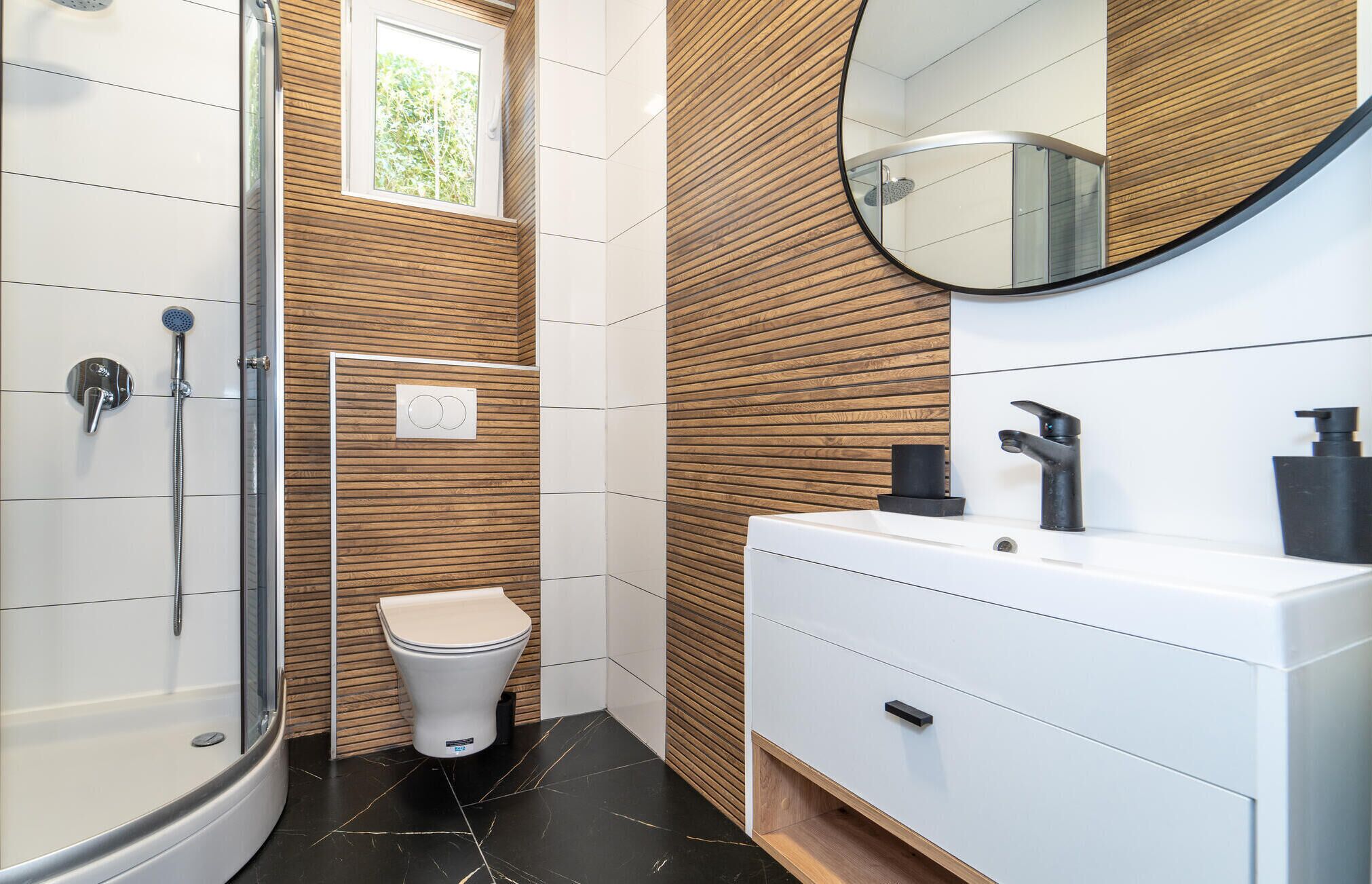 A modern bathroom with a glass-enclosed shower, a toilet, and a vanity with a mirror.