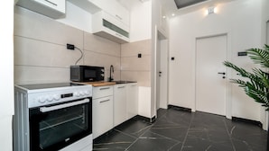 Een moderne keuken met witte kasten, een zwarte magnetron, een fornuis en een spoelbak.