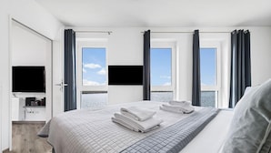 A hotel room with a bed, a TV, a desk with a computer, and a view of the sea. - 2 bedroom cozy apartment in Olpenitz (Olpenitz)
