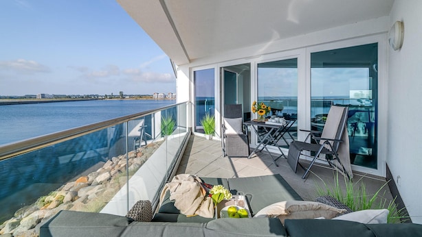A balcony with a view of the water, outdoor seating, and a table with items on it. - 2 bedroom cozy apartment in Olpenitz (Olpenitz)
